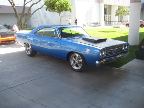 1998 Ford Crown Victoria - A blue 1969 Plymouth Road Runner is parked outside a building, with another vehicle visible to the left.