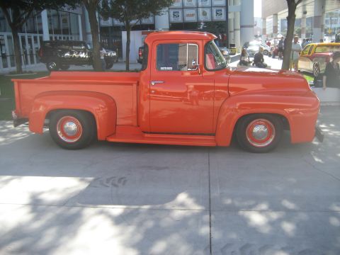 1998 Ford Crown Victoria - This orange Ford F-100 pickup truck is parked on a concrete surface.