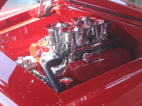 1998 Ford Crown Victoria - Close-up view of a custom engine bay polished chrome intake stacks and bright red valve covers.
