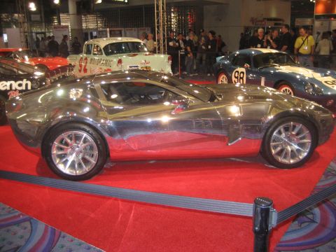 1998 Ford Crown Victoria - A highly reflective custom car is displayed on a red carpet, with other vehicles and spectators visible.