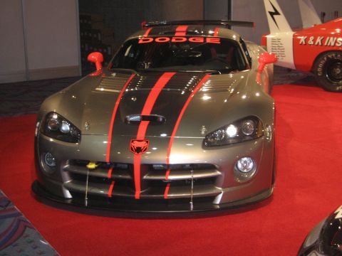 1998 Ford Crown Victoria - A gray Dodge Viper with red racing stripes is parked on a red carpet, with another vehicle visible to the right.