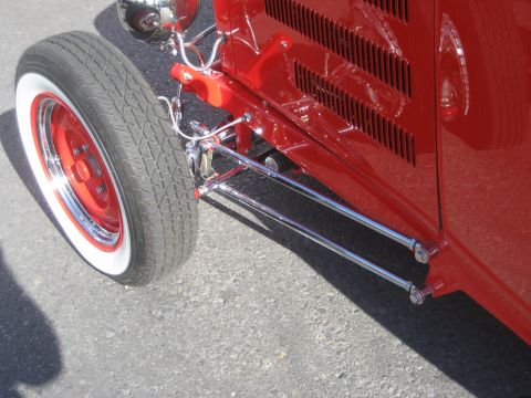 1998 Ford Crown Victoria - Close-up view of a red hot rod's front wheel and side panel, showing custom suspension details.