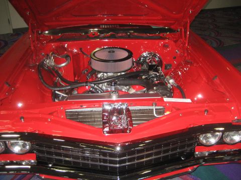 1998 Ford Crown Victoria - Customized engine bay of a red 1967 Chevrolet Impala, a V8 engine and polished components.