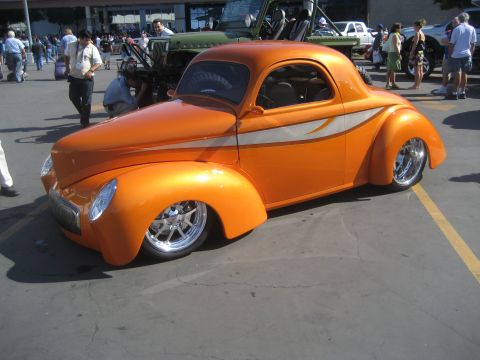 1998 Ford Crown Victoria - A custom orange coupe with a distinctive body style and chrome wheels is shown from the front-front-three-quarter view.