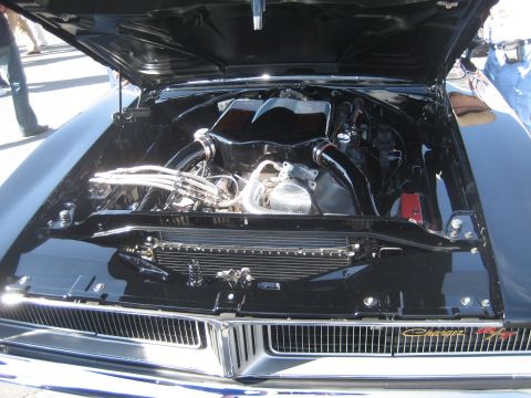 1998 Ford Crown Victoria - Engine bay of a black muscle car, dual intakes and a Charger R/T badge on the grille.