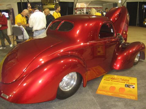 1998 Ford Crown Victoria - A shiny red custom coupe with its hood and trunk open sits on display at an indoor event.