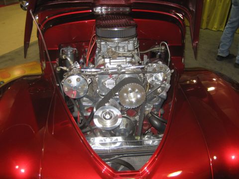 1998 Ford Crown Victoria - The engine bay of a custom red car is open, revealing a powerful engine with chrome accents.
