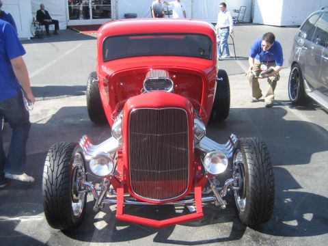 1998 Ford Crown Victoria - A custom red hot rod is displayed with its prominent chrome grille and engine details visible.