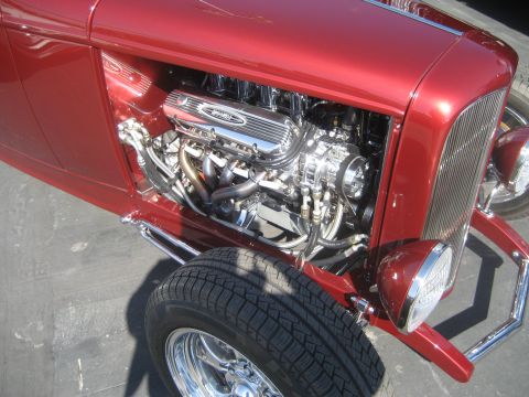 1998 Ford Crown Victoria - Close-up of a shiny V8 engine in a red hot rod, showing chrome details and exhaust headers.