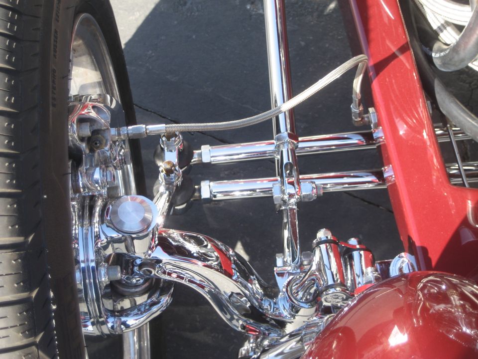 Chrome suspension and brake detail on a red hot rod front wheel