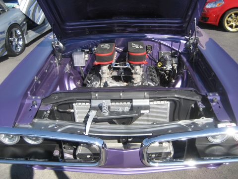 1998 Ford Crown Victoria - Engine bay of a custom purple muscle car, dual carburetors and a polished radiator.