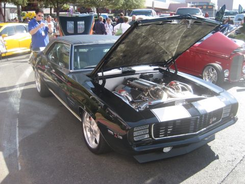 1998 Ford Crown Victoria - A black 1969 Chevrolet Camaro Z28 is displayed with its hood open, a highly customized engine bay.