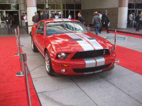 1998 Ford Crown Victoria - This red Ford Mustang Shelby GT500 has silver racing stripes and is on display.