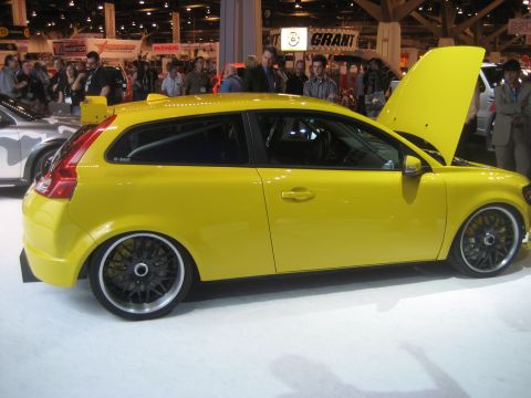 1998 Ford Crown Victoria - A yellow Volvo C30 is displayed with its hood open at an indoor event.