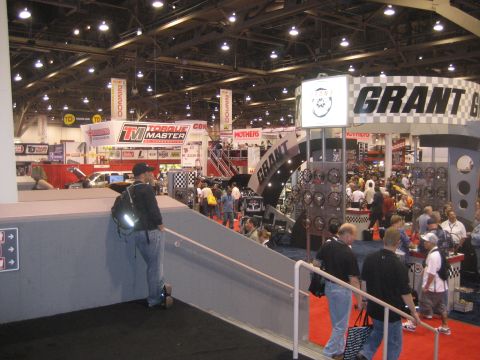 1998 Ford Crown Victoria - A bustling trade show floor features displays from Grant steering wheels and Torque Master, with attendees browsing the exhibits.