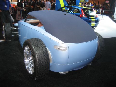 1998 Ford Crown Victoria - A light blue custom roadster concept car is displayed indoors with other vehicles in the background.