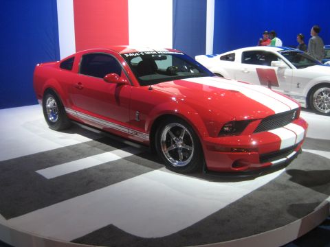 1998 Ford Crown Victoria - Red Ford Mustang GT500 on display with another Mustang behind it.
