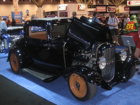 1998 Ford Crown Victoria - A black hot rod coupe is displayed with its hood open, revealing the engine and tan interior.
