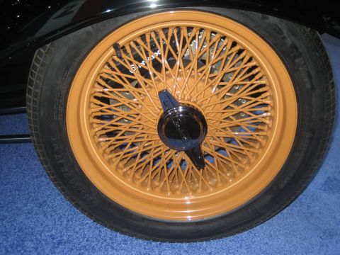 1998 Ford Crown Victoria - Close-up of a tan wire wheel with a chrome hubcap, set against a blue carpeted surface.