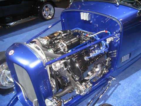 1998 Ford Crown Victoria - A custom blue hot rod displays its polished V8 engine and supercharger, with another vehicle visible in the background.