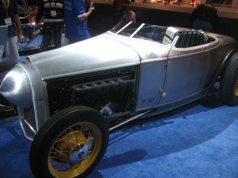 1998 Ford Crown Victoria - A custom hot rod with a polished metal body and a V8 engine is displayed on a blue carpet.
