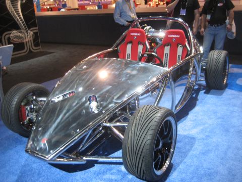1998 Ford Crown Victoria - This custom-built vehicle features a polished chrome exoskeleton and bright red racing seats, displayed indoors on a blue carpet.