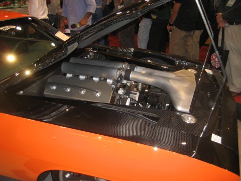 1998 Ford Crown Victoria - The engine bay of an orange car features a custom intake system and carbon fiber detailing.