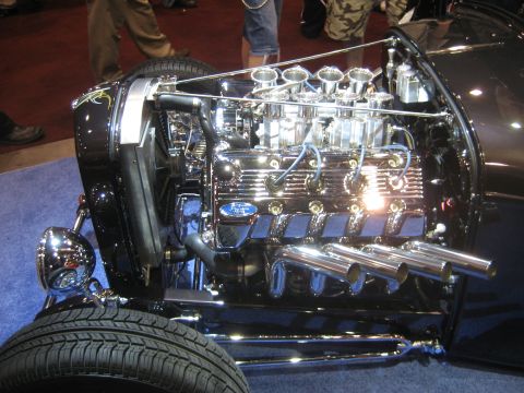 1998 Ford Crown Victoria - A highly polished Ford V8 engine with multiple carburetors and exhaust pipes is displayed.