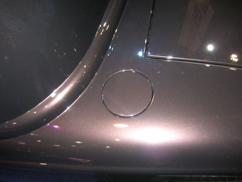 1998 Ford Crown Victoria - Close-up of a dark gray metallic car door, showing the circular fuel filler door and reflections.
