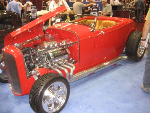 1998 Ford Crown Victoria - A bright red hot rod convertible is displayed with its hood open, revealing a chrome engine and exhaust system.