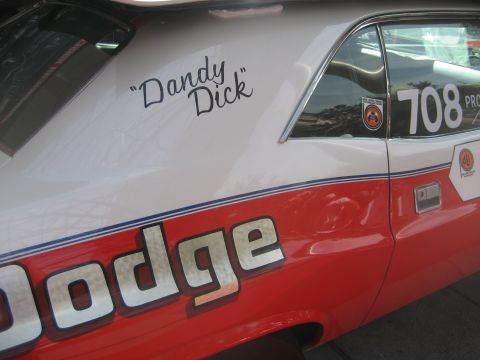 1998 Ford Crown Victoria - A vintage Dodge muscle car displays racing livery and a driver's name on its side.