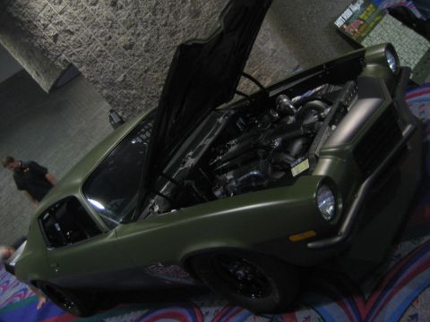1998 Ford Crown Victoria - A customized olive green muscle car is displayed with its hood open, revealing the engine and custom modifications.
