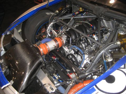 1998 Ford Crown Victoria - Close-up view of a racing car's engine bay, a V8 engine, carbon fiber intake, and a racing tire.