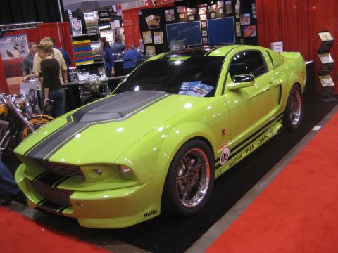 1998 Ford Crown Victoria - Lime green Ford Mustang on display at an auto show with racing stripes and various decals.
