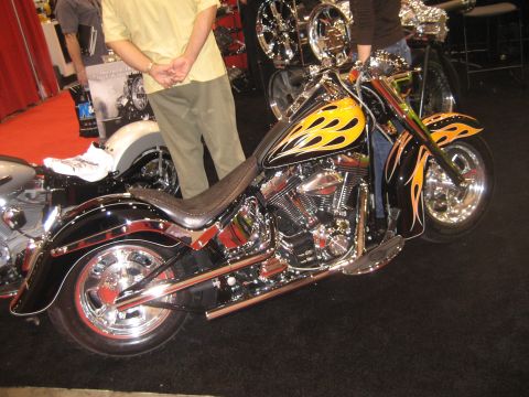 1998 Ford Crown Victoria - A custom motorcycle with flame graphics is displayed indoors on a black carpeted floor.
