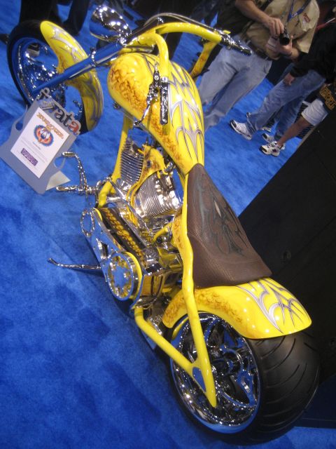 1998 Ford Crown Victoria - A custom yellow motorcycle with flame graphics is displayed on a blue carpeted surface.