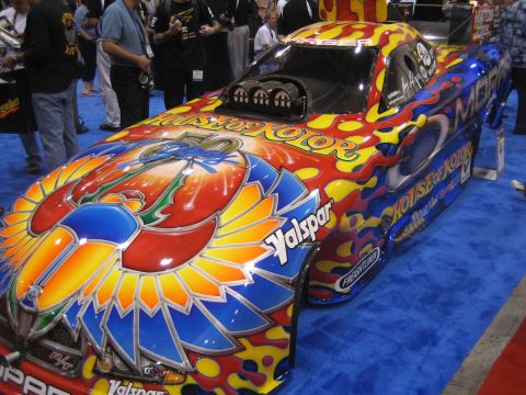 1998 Ford Crown Victoria - A highly customized drag racing car displays vibrant flame and abstract wing graphics on a blue carpeted floor.