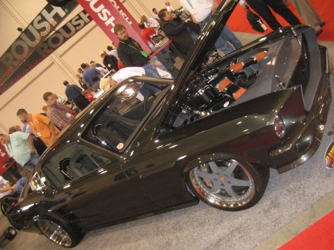 1998 Ford Crown Victoria - A custom dark green coupe with its hood open, revealing the engine and custom wheels, at an indoor event.