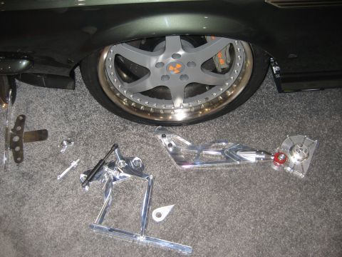 1998 Ford Crown Victoria - Custom chrome suspension components and a large aftermarket wheel with orange brake calipers are laid out on the carpet.