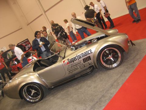 1998 Ford Crown Victoria - A silver Shelby Cobra replica is displayed with its hood open, revealing the engine and various performance decals on its side.