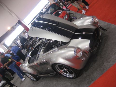 1998 Ford Crown Victoria - Silver AC Cobra replica with black racing stripes and open hood at a car show.