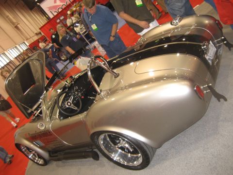 1998 Ford Crown Victoria - A silver Shelby Cobra replica with black stripes is shown with its doors open at an event.