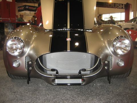 1998 Ford Crown Victoria - A silver Shelby Cobra replica is displayed with its hood open, showing off its large radiator and racing stripes.