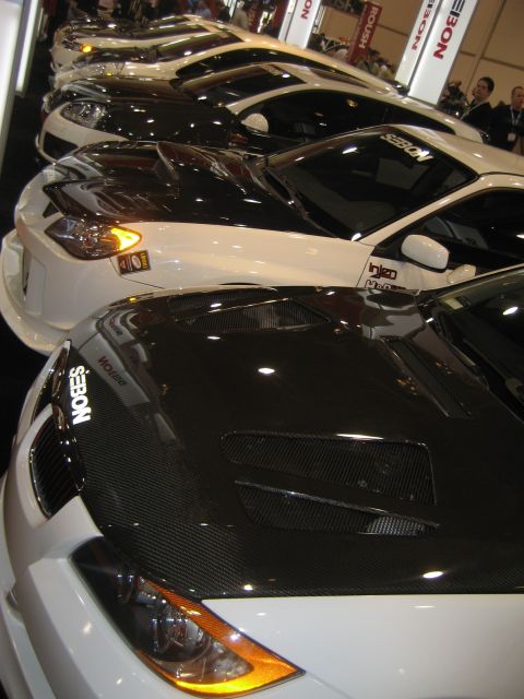 1998 Ford Crown Victoria - Multiple modified sports cars displayed in a row at an automotive event.