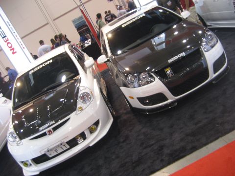 1998 Ford Crown Victoria - Two modified cars, a white Honda Fit and a white Volkswagen GTI, are displayed indoors with carbon fiber hoods.