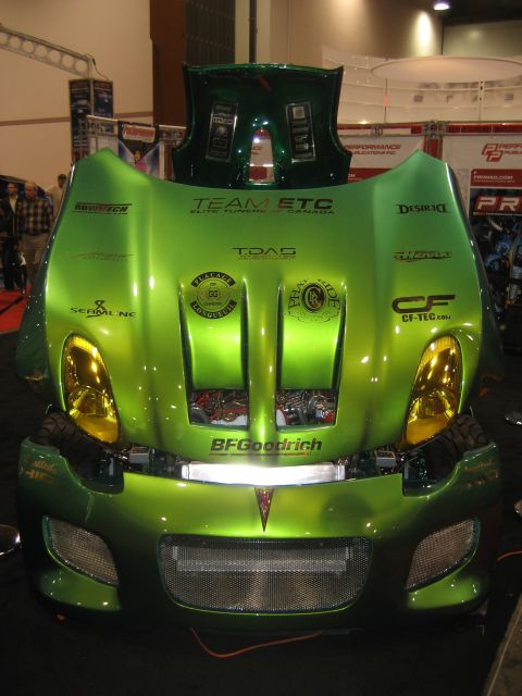 1998 Ford Crown Victoria - A heavily modified green car with its hood open, displaying custom paint and aftermarket parts.