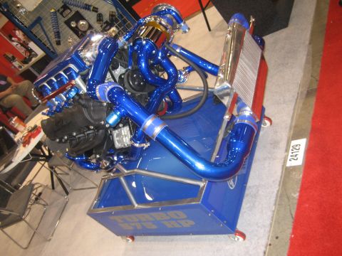 1998 Ford Crown Victoria - A custom-built engine with extensive blue piping and a large intercooler is displayed on a stand.
