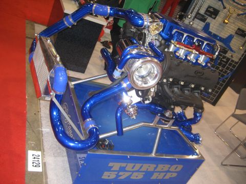1998 Ford Crown Victoria - A custom-built engine display a prominent turbocharger and vibrant blue piping, labeled with "TURBO 575 HP".