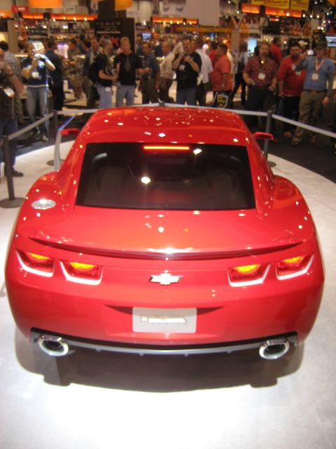 1998 Ford Crown Victoria - A red Chevrolet Camaro concept car is displayed indoors with a crowd in the background.