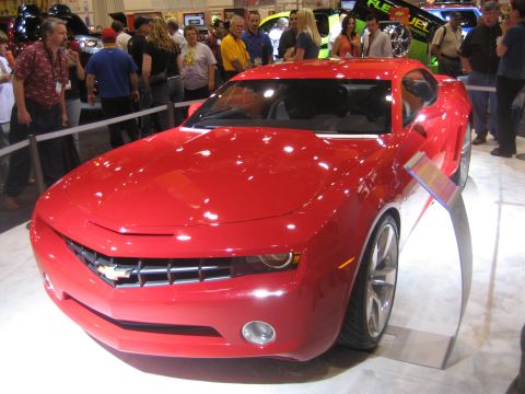 1998 Ford Crown Victoria - A bright red sports car is displayed at an auto show, with people in the background.